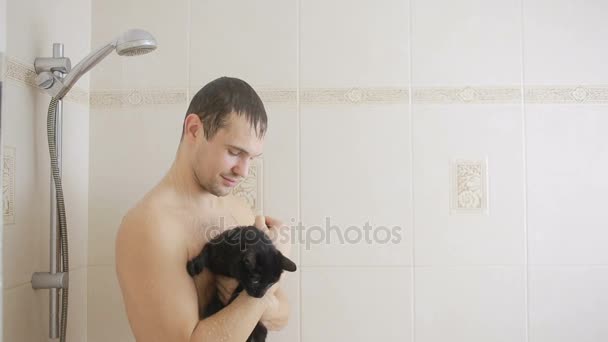 Um homem a tomar um duche com um gato preto. close-up — Vídeo de Stock