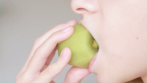 Close-up van een kind ontvangt voedsel. eten. het eten van fruit, bijt Kiwi. — Stockvideo