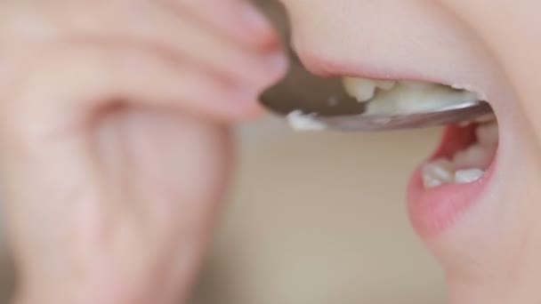 El primer plano del niño recibe la comida. comiendo. come cuchara de gachas de leche — Vídeo de stock