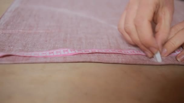Mãos de uma costureira. fita métrica seamstress aplica-se ao tecido . — Vídeo de Stock