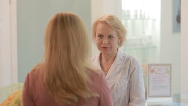 Mujer sosteniendo un ramo de flores. hablar con un médico en un pasillo del hospital — Vídeos de Stock