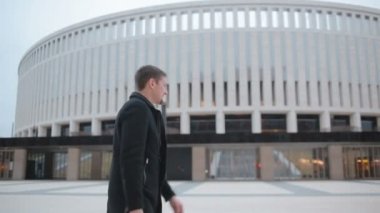 bir telefonla gökdelenler arka plan üzerinde modern bir şehirde paltolu adam