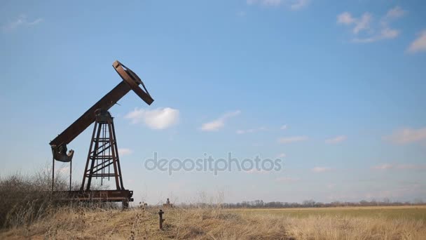 Broken and abandoned oil pump on a background of blue sky and white clouds. — Stock Video