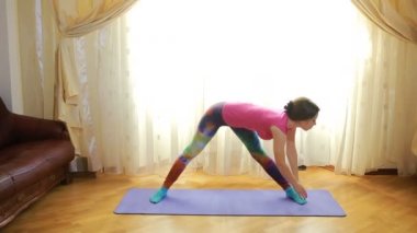 Evde esneme egzersizleri yapan genç bir kadın.