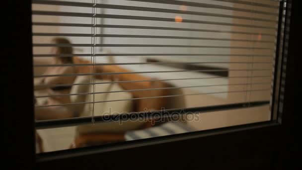 Alguien espiando a una chica de la calle a través de las persianas de la ventana. delincuencia — Vídeo de stock