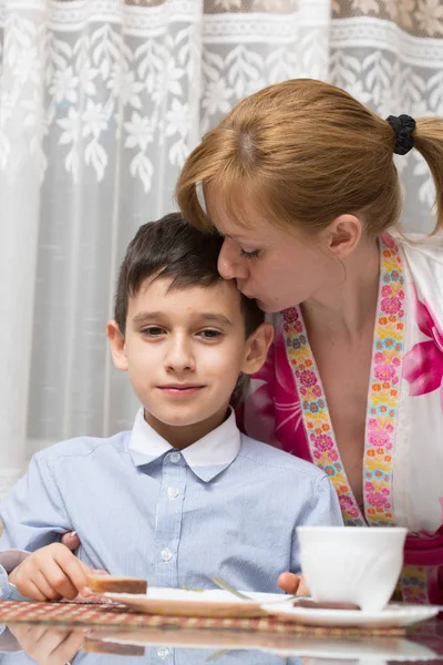 Joven feliz hermosa madre y su hijo comiendo desayuno saludable — Foto de Stock