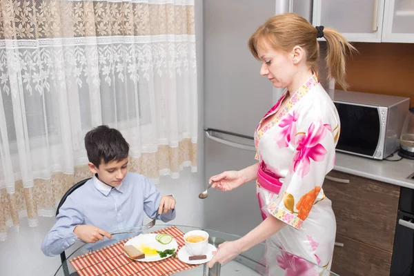 Junge glückliche schöne Mutter und ihr Kind essen gesundes Frühstück — Stockfoto