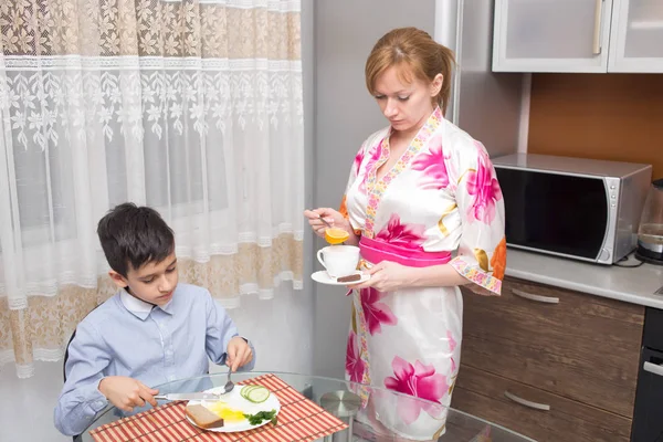 Junge glückliche schöne Mutter und ihr Kind essen gesundes Frühstück — Stockfoto