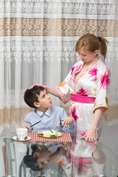 Joven feliz hermosa madre y su hijo comiendo desayuno saludable —  Fotos de Stock