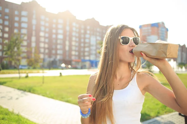 Meisje drinkt uit een fles in een papieren zak. — Stockfoto