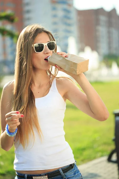 Ragazza beve da una bottiglia in un sacchetto di carta . — Foto Stock