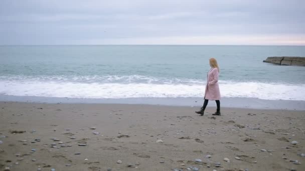 Chica feliz con abrigo rosa cerca del mar durante una tormenta. viento fuerte . — Vídeos de Stock