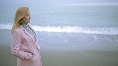 Mutlu kız pembe ceket bir fırtına sırasında deniz kenarında. güçlü Rüzgar.