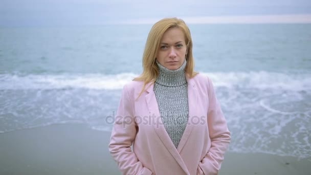 Happy girl in pink coat near the sea during a storm. strong wind. — Stock Video