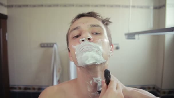 Guy shaving off his beard with a razor in the bathroom — Stock Video