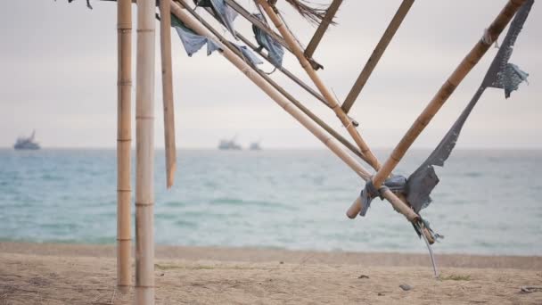Összecsukott napellenző bambusz egy elhagyatott tengerparton. Nem a szezon, ökológia fogalma — Stock videók
