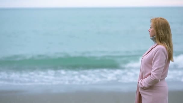 Chica feliz con abrigo rosa cerca del mar durante una tormenta. viento fuerte . — Vídeo de stock