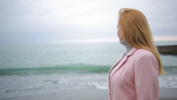 Szczęśliwa dziewczyna w różowy płaszcz, w pobliżu morza podczas burzy. silny wiatr. — Wideo stockowe