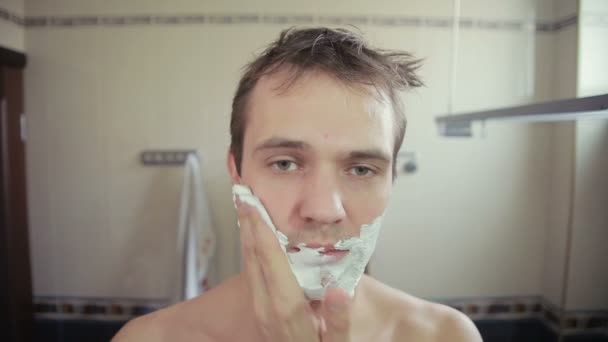 Chlap oholil vousy s břitvou v koupelně — Stock video