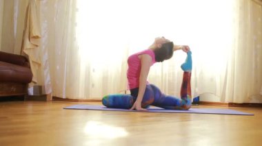 Evde esneme egzersizleri yapan genç bir kadın.