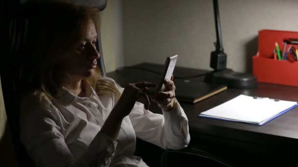女人坐在餐桌的办公室和在智能手机上留言. — 图库视频影像