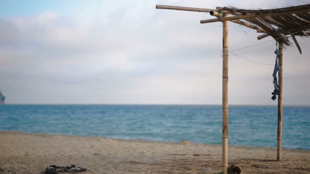 Eingestürzte Markise aus Bambus an einem verlassenen Strand. nicht die Saison, ökologisches Konzept — Stockvideo