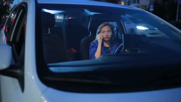 Девушка вечером разговаривает по телефону, сидя в машине — стоковое видео