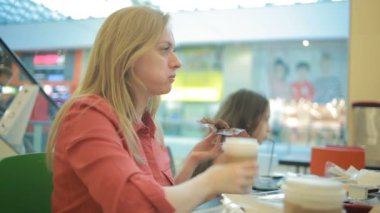 Şişman bir kadın bir kafede bir kek yiyor ve kahve sips