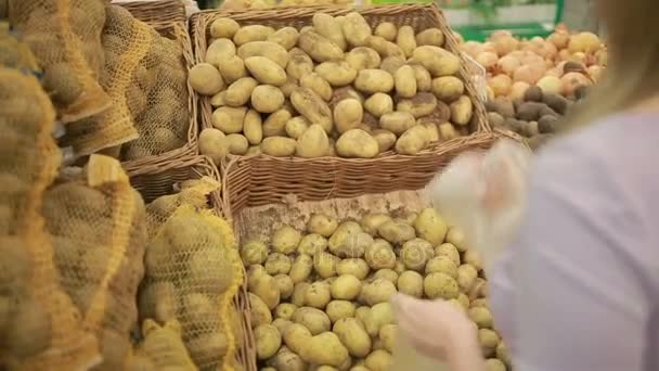 Egy nő egy szupermarket, egy növényi polc, vásárlási zöldség, burgonya — Stock videók