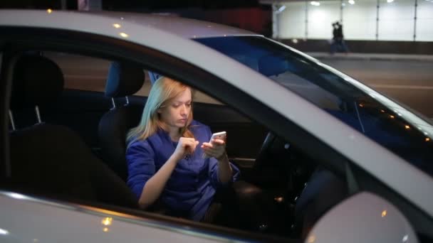 Meisje in de avond praten over de telefoon zittend in de auto — Stockvideo