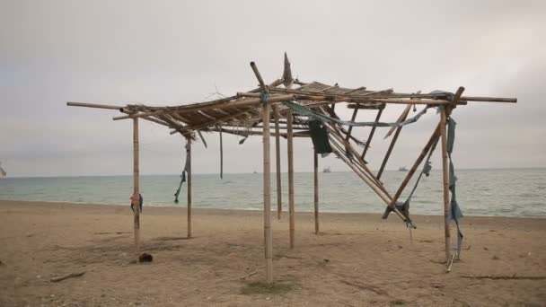 Toldo de bambu em colapso em uma praia abandonada. Não a estação, conceito de ecologia — Vídeo de Stock