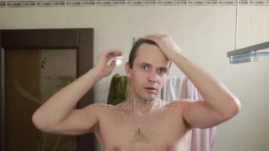 Genç çekici adam uzaklaşıyorsun saç çizgisi banyoda olup olmadığını denetler. Kellik