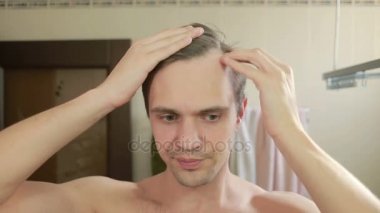 Genç çekici adam uzaklaşıyorsun saç çizgisi banyoda olup olmadığını denetler. Kellik