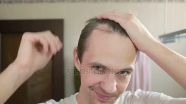 Genç çekici adam uzaklaşıyorsun saç çizgisi banyoda olup olmadığını denetler. Kellik