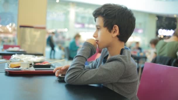Joven adolescente jugando juego en el teléfono inteligente en la cafetería — Vídeo de stock