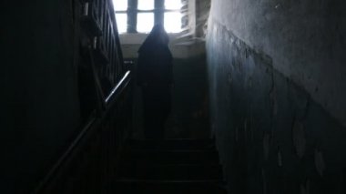Siyah kapüşonlu bir erkekte bir mahallede bir örümcek ağı ile korkunç bir eski ev ile.