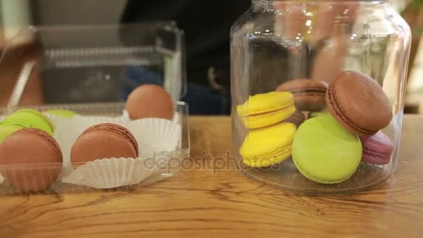 Gekleurde amandel koekjes met een glazen afdekplaat in de vitrine. Desserts van cafés — Stockvideo