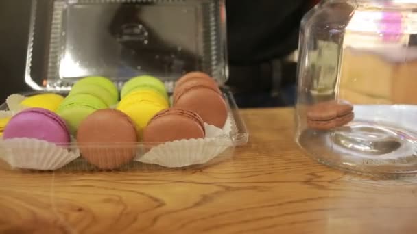 Gekleurde amandel koekjes met een glazen afdekplaat in de vitrine. Desserts van cafés — Stockvideo