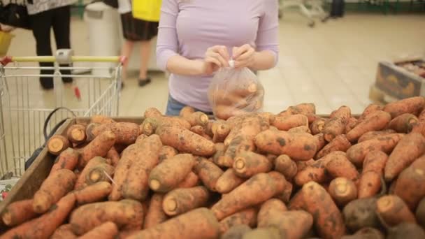 Una mujer en un supermercado en un estante de verduras, comprando verduras  . — Vídeos de Stock