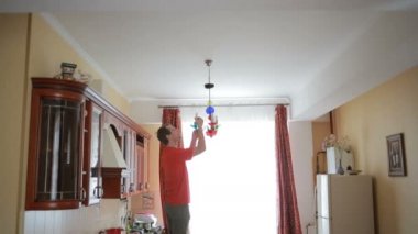 Yakışıklı erkek gömlek bir ampul bir kristal lamba için değiştirir.