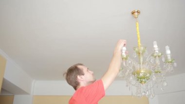 Yakışıklı erkek gömlek bir ampul bir kristal lamba için değiştirir.