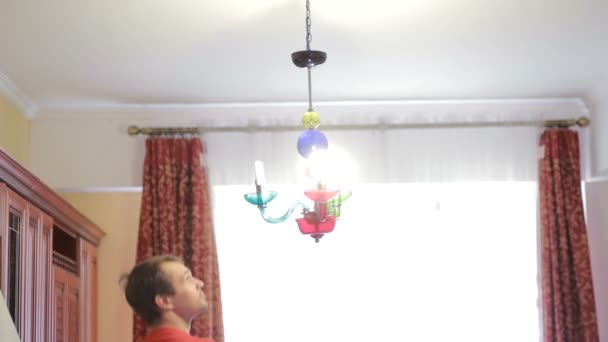 Een knappe man shirt verandert een gloeilamp in een lamp kristal — Stockvideo