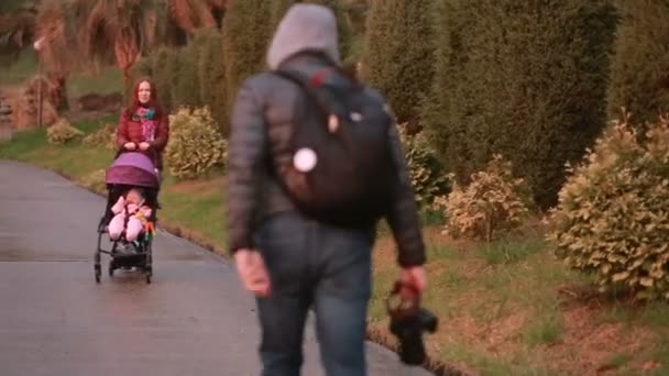 Maman et papa, jouant avec leur enfant, assis dans une poussette : marcher dans le parc — Video