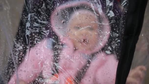 Mamá y papá jugando con su bebé sentado en el cochecito: protección contra la lluvia — Vídeos de Stock