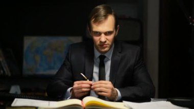 Kötü iş adamı, resmi, tehditkar bir şekilde ofis masasında otururken kameraya bakıyor