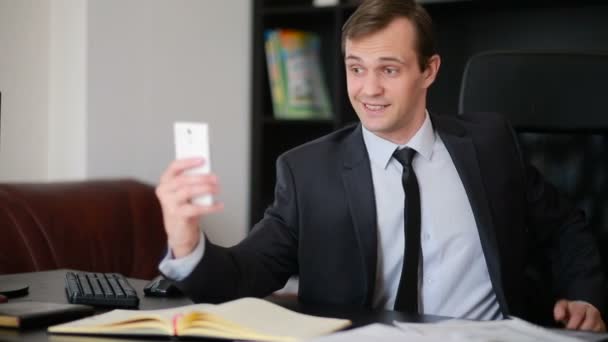 Attractive business man talking on the phone doing selfie at the office — Stock Video