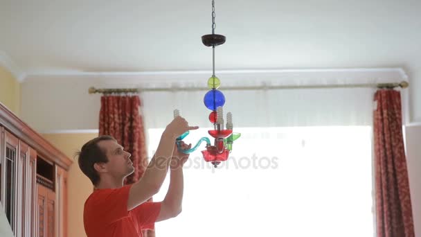 Pohledný muž košile mění žárovku do křišťálové lampy — Stock video