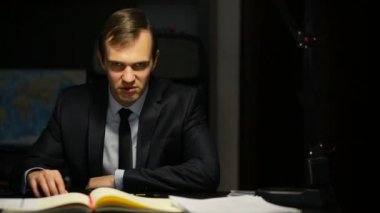 Kötü iş adamı, resmi, tehditkar bir şekilde ofis masasında otururken kameraya bakıyor