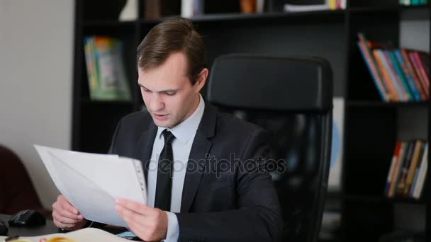 Ελκυστικό επιχειρηματικό άνθρωπος που εργάζονται με έναν υπολογιστή και τα έγγραφα στο γραφείο — Αρχείο Βίντεο
