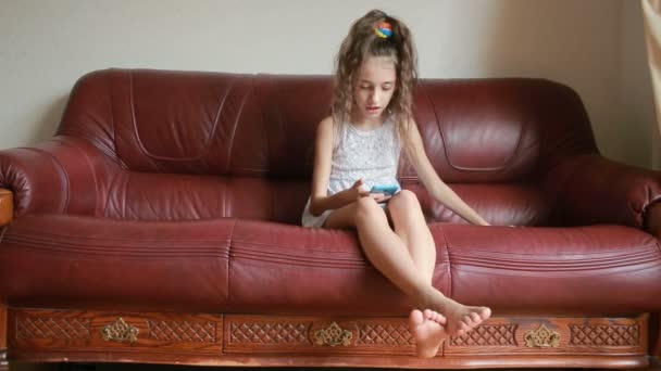 Liten flicka gör selfie på smartphone hemma på soffan — Stockvideo